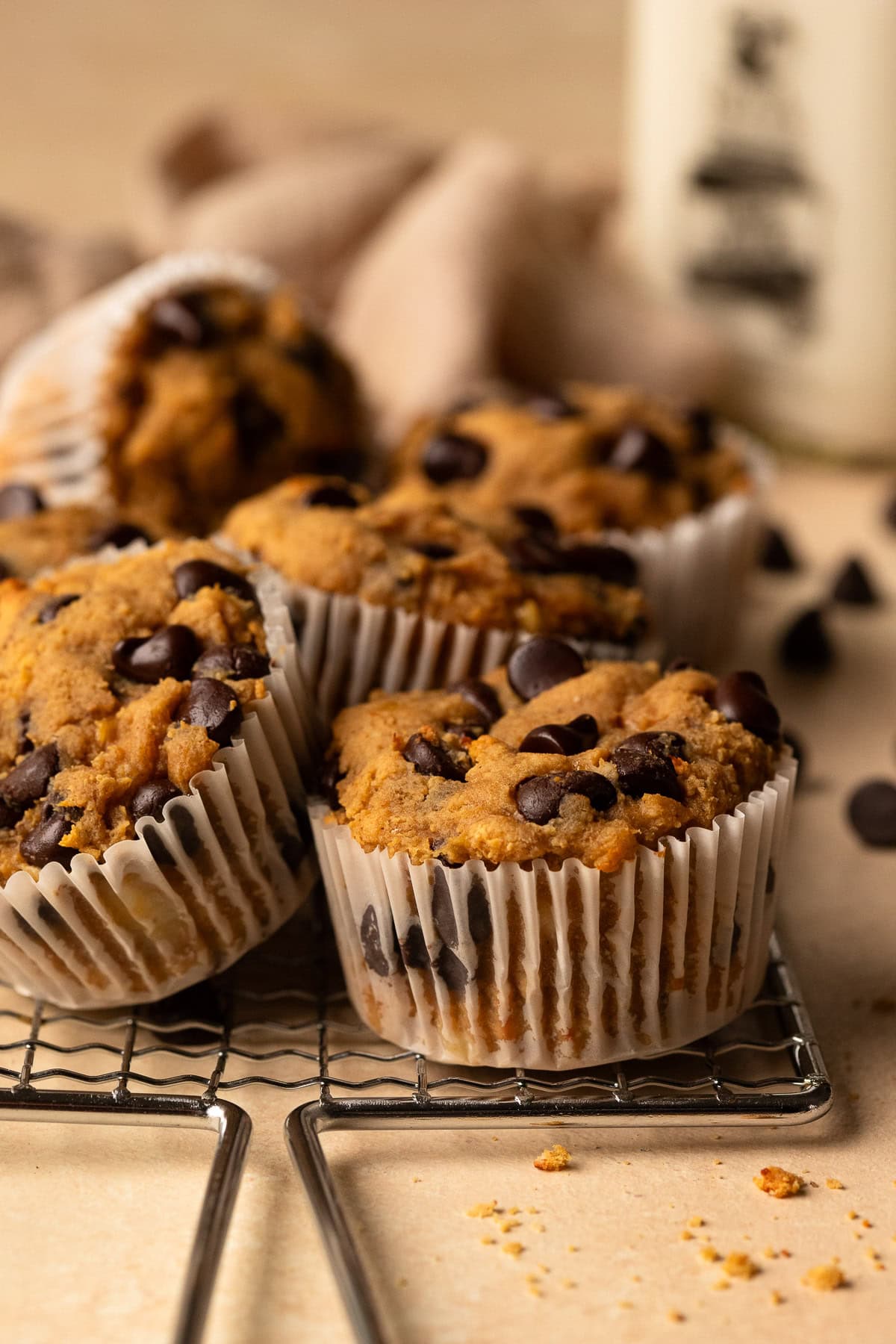 Six muffins on a safety grater, with chocolate chips and a glass milk bottle in the background.